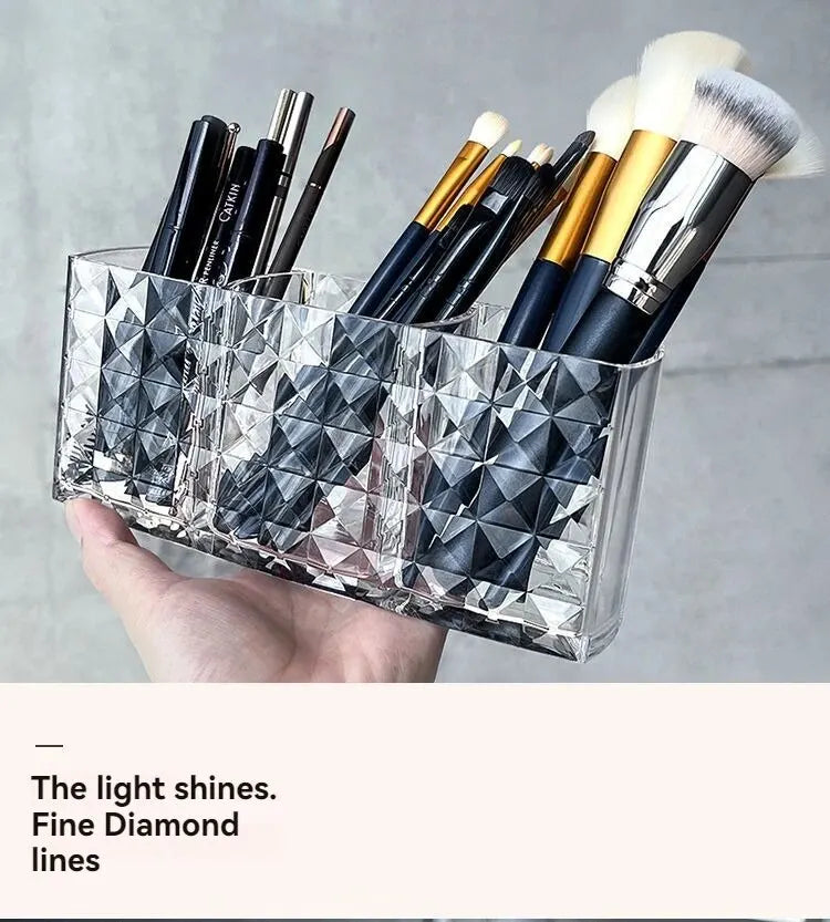Clear acrylic makeup brush holder with three compartments filled with various makeup brushes