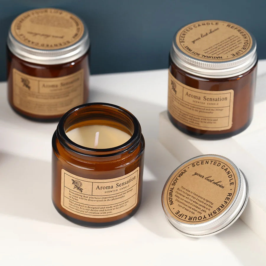 Three jars of Aroma Sensation scented soy wax candles in brown glass cups displayed on a white surface.