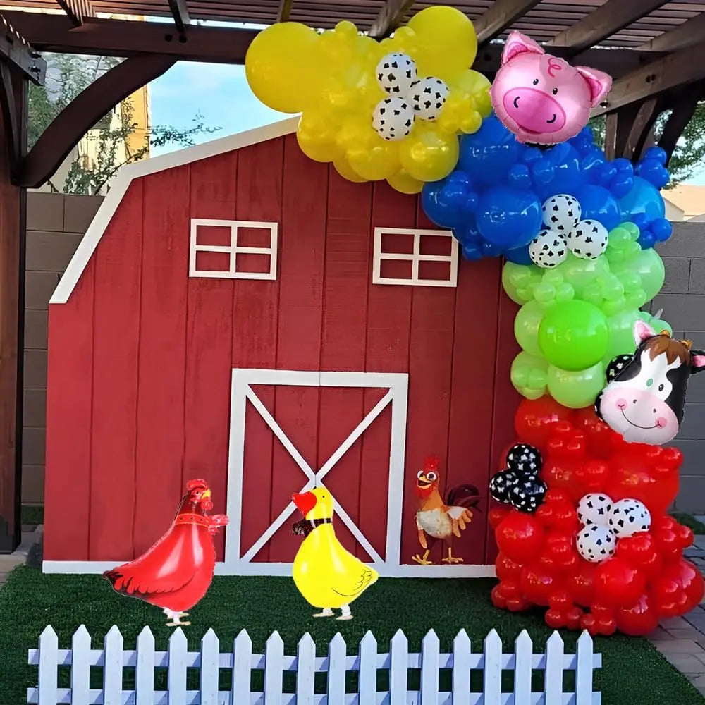 A vibrant balloon garland featuring a pink pig and cow print balloons decorating a red barn facade.