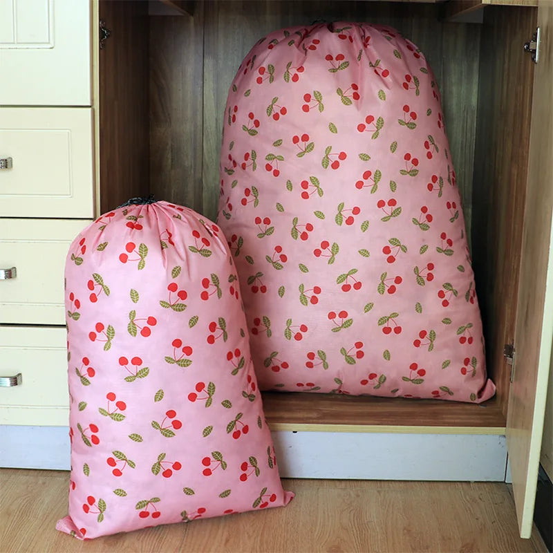A pink drawstring storage bag with a red berry pattern is displayed in a wooden cabinet.