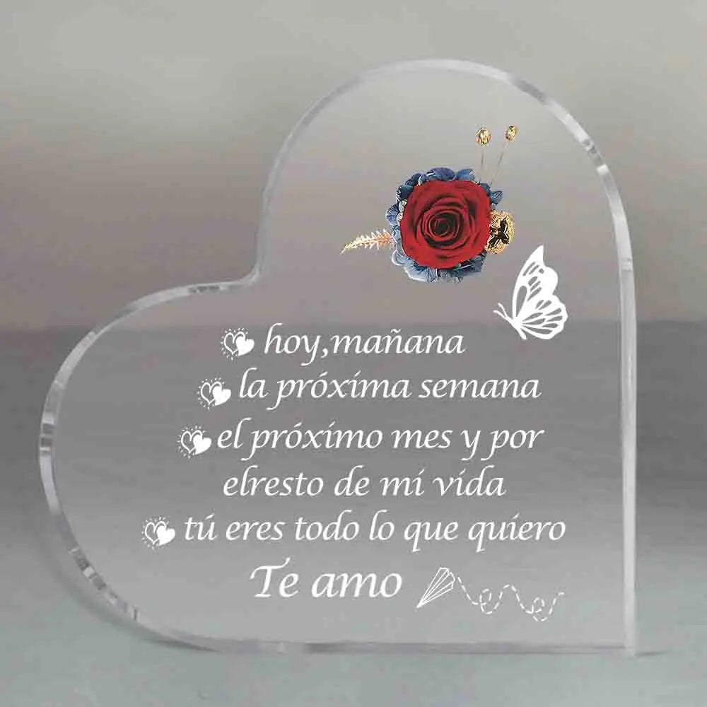 Placa de acrílico con forma de corazón grabada con una rosa roja y una mariposa, con texto en español que expresa amor.