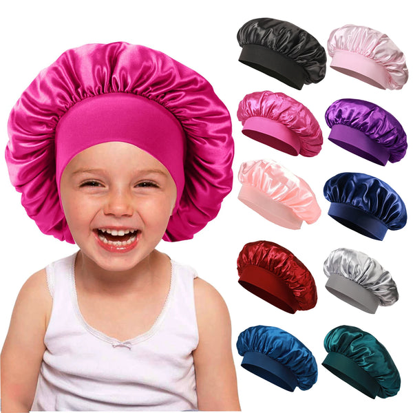 A toddler is smiling while wearing a bright pink satin sleep bonnet, with various colored bonnets shown nearby.