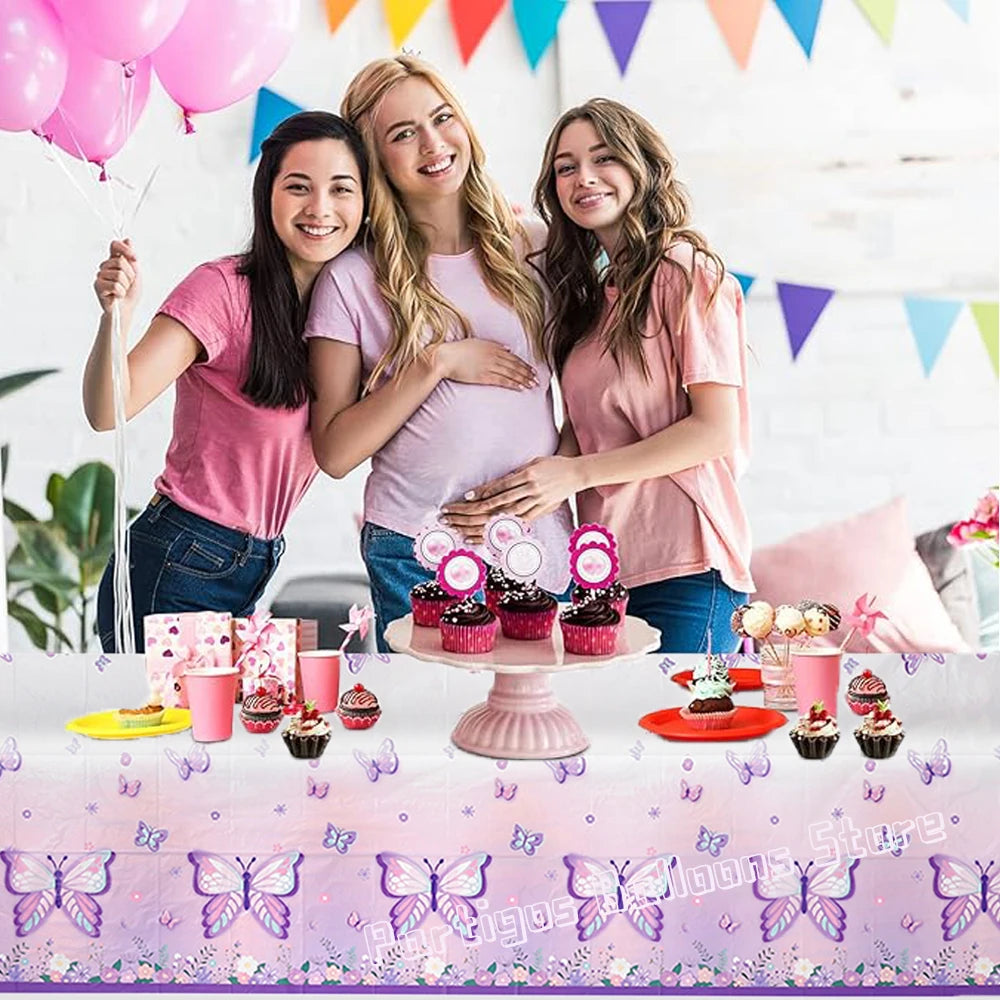 Trois femmes souriantes posant avec une nappe à motif papillon aquarelle pour des fêtes.