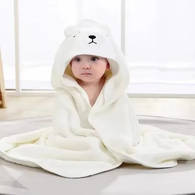 Baby trägt ein weißes Kapuzenhandtuch- und Wickelset mit Bärengesicht-Design.