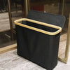 A black bamboo storage basket with a wooden handle and lid is displayed on a marble surface.