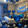 A ceiling decorated with blue and silver balloons shaped like hearts for a birthday party.