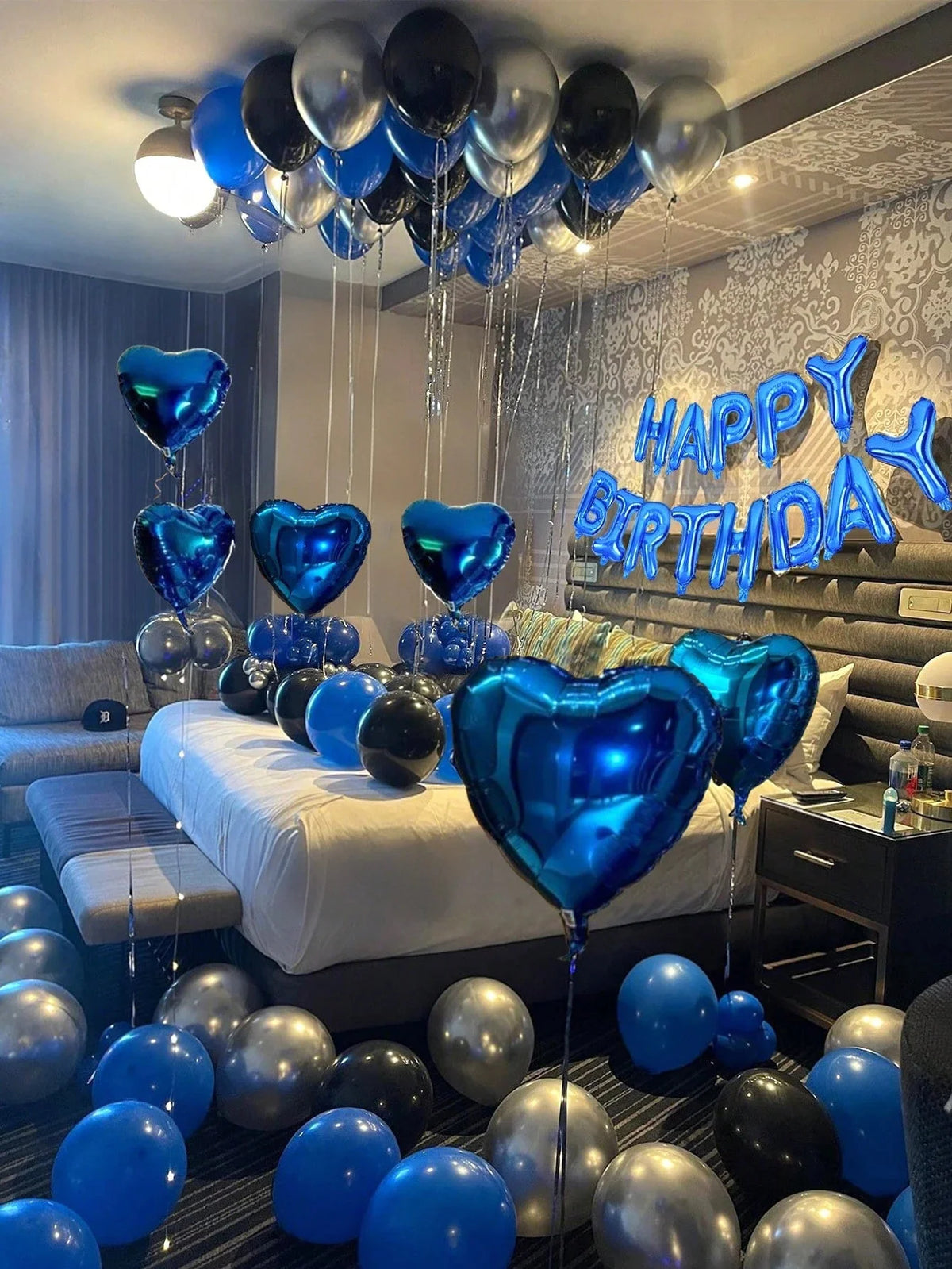 A ceiling decorated with blue and silver balloons shaped like hearts for a birthday party.