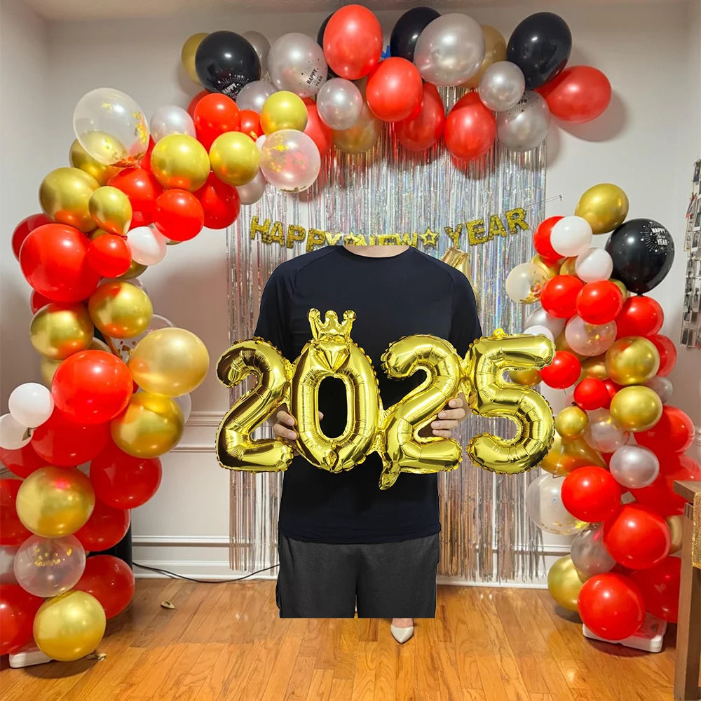 A person stands in front of a balloon arch display featuring red, gold, and white balloons with a '2025' decoration.