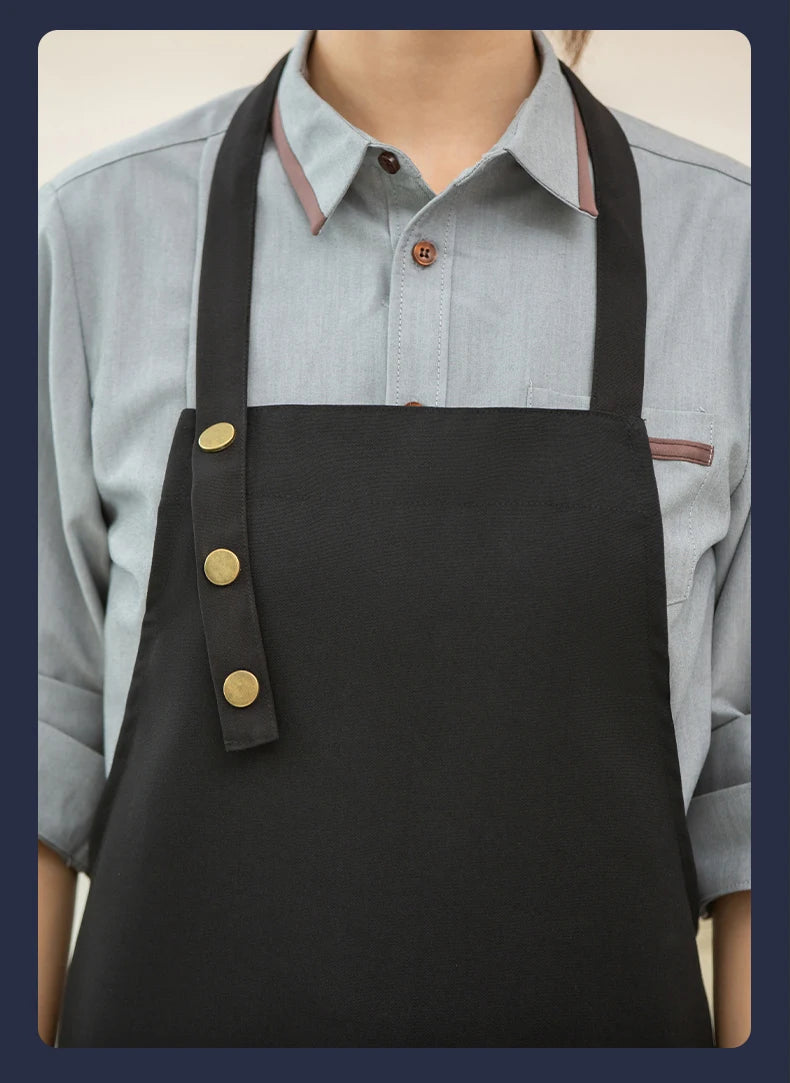 A black canvas apron with adjustable straps is worn over a light blue collared shirt.