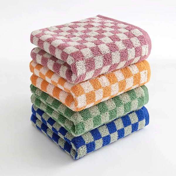 A stack of plaid cotton bath towels in various colors including pink, orange, and green.