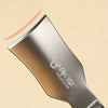 A close-up view of a stainless steel corn kernel remover peeler with a reddish line indicating action.