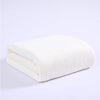 A stack of thick white microfiber bath towels folded neatly on a white surface.