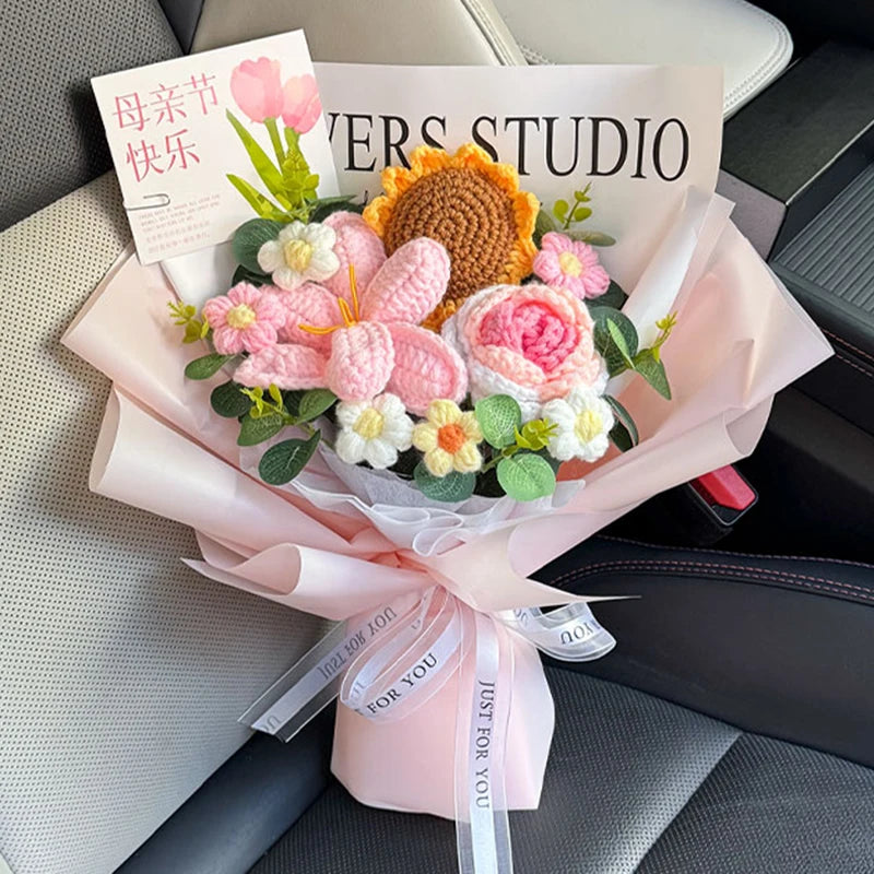 A bouquet of handmade crochet flowers in pink and yellow tones is presented in a light pink paper wrap.