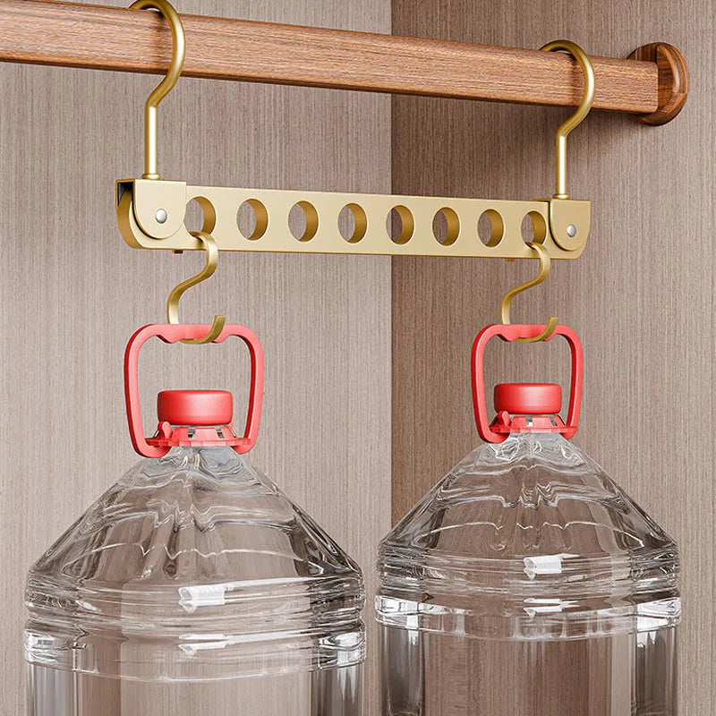 A foldable storage rack with hangers is hanging from a wooden rod against a light brown background.