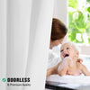 A young child is laughing while being washed with a white towel in a bright bathroom setting.
