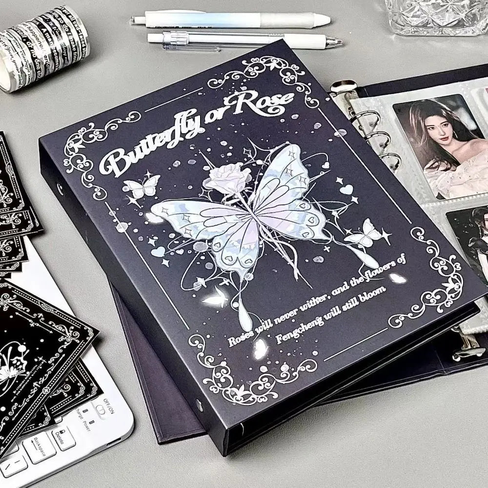 A dark photo album featuring a butterfly design and text on the cover, surrounded by writing tools and other stationery.