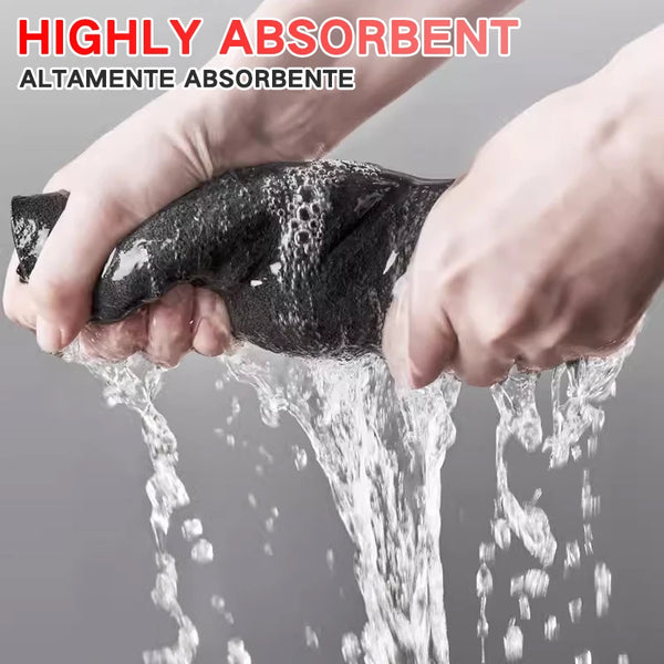 Hands are washing a black, highly absorbent cleaning cloth under running water.