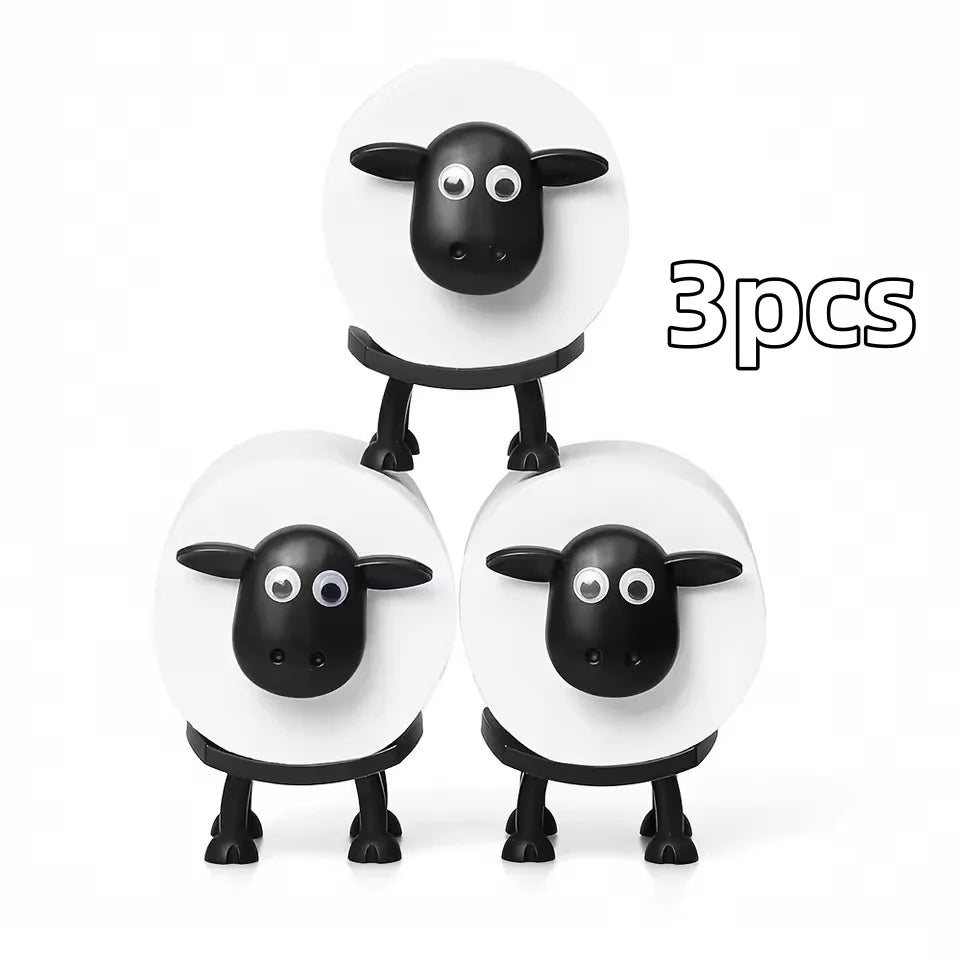 Three black and white decorative toilet paper holders shaped like cows.