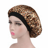 A woman wearing a satin sleep bonnet with a leopard print pattern.