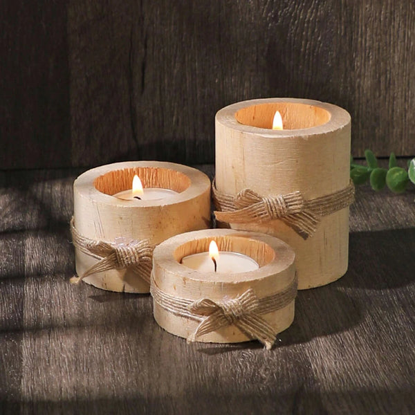 Drei natürliche Holzscheite, umwickelt mit Schnur, dienen als Teelampenhalter für Dekoration.