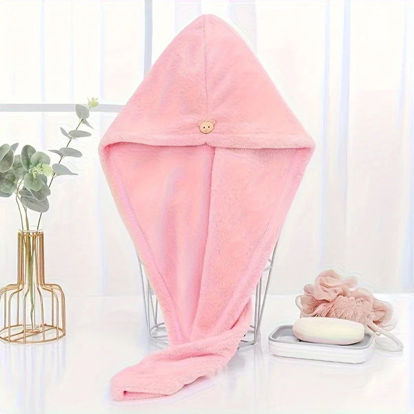 A pink microfiber hair drying wrap towel displayed on a clear stand next to a plant.
