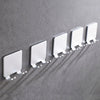 A row of white aluminum shaving razor storage racks mounted on a gray wall.