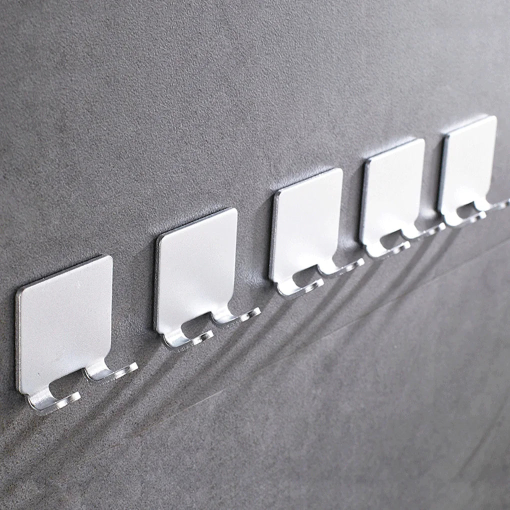 A row of white aluminum shaving razor storage racks mounted on a gray wall.