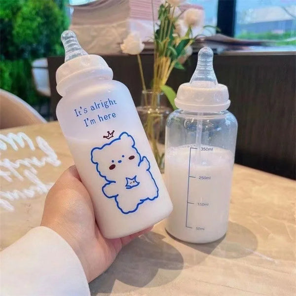 A hand holds a white plastic bottle of liquid labeled It's alright I'm here, next to a clear bottle.