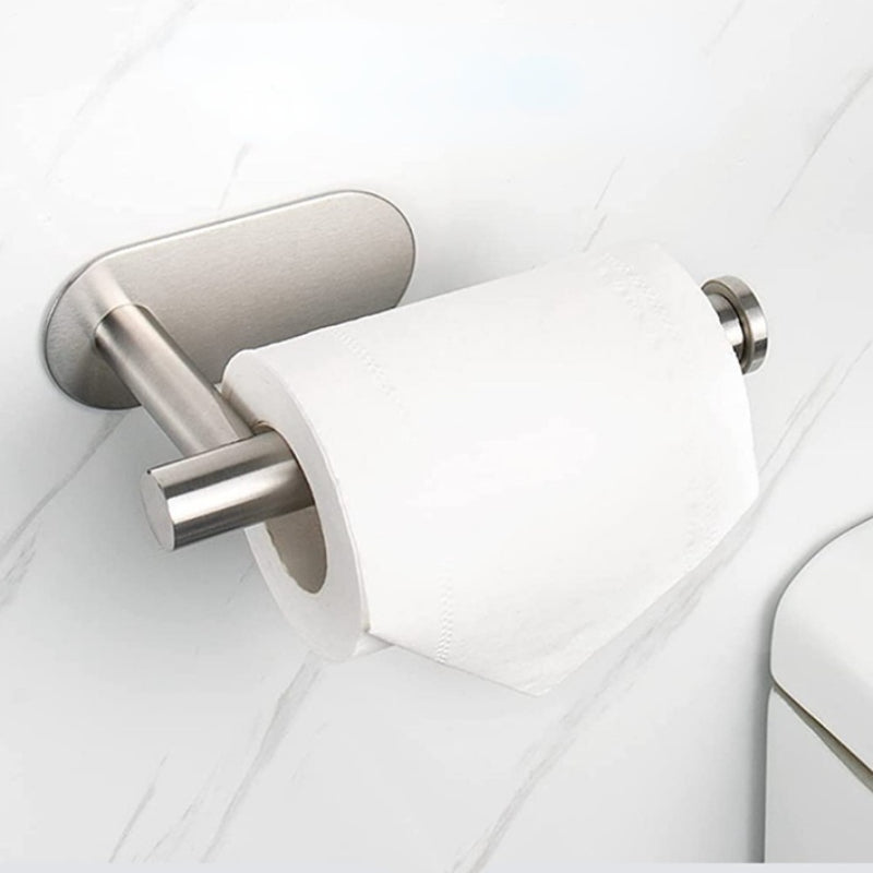 A silver wall mounted toilet paper holder with a white roll of toilet paper on a white marble surface.