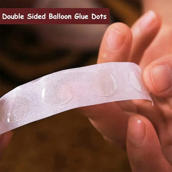 A hand holds a clear double-sided balloon glue dot for crafting.