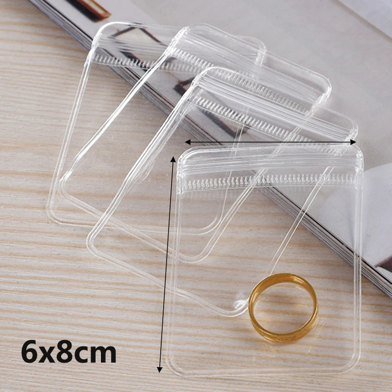 A clear PVC zip lock jewelry pouch is shown on a wooden surface, demonstrating its size and design.