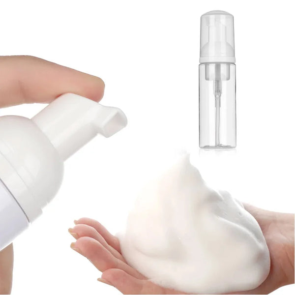 A hand is squeezing a white foam cleanser from a pump bottle, with another bottle visible in the background.