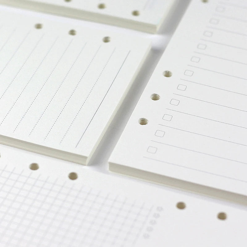 Close-up view of white loose leaf notebook refill paper with ruled lines and dotted guides.