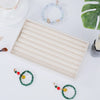A velvet jewelry organizer tray with a drawer is shown with various beaded and gold jewelry items on a white surface.