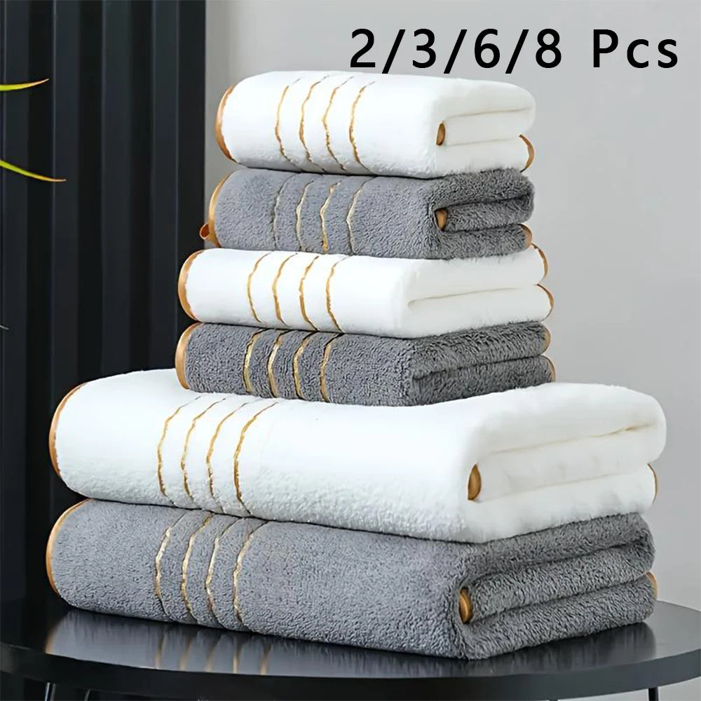 A stack of eight white and gray bath towels is displayed on a dark surface.