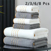 A stack of eight white and gray bath towels is displayed on a dark surface.