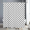 White shower curtain with a black polka dot pattern hanging on a metal rod.