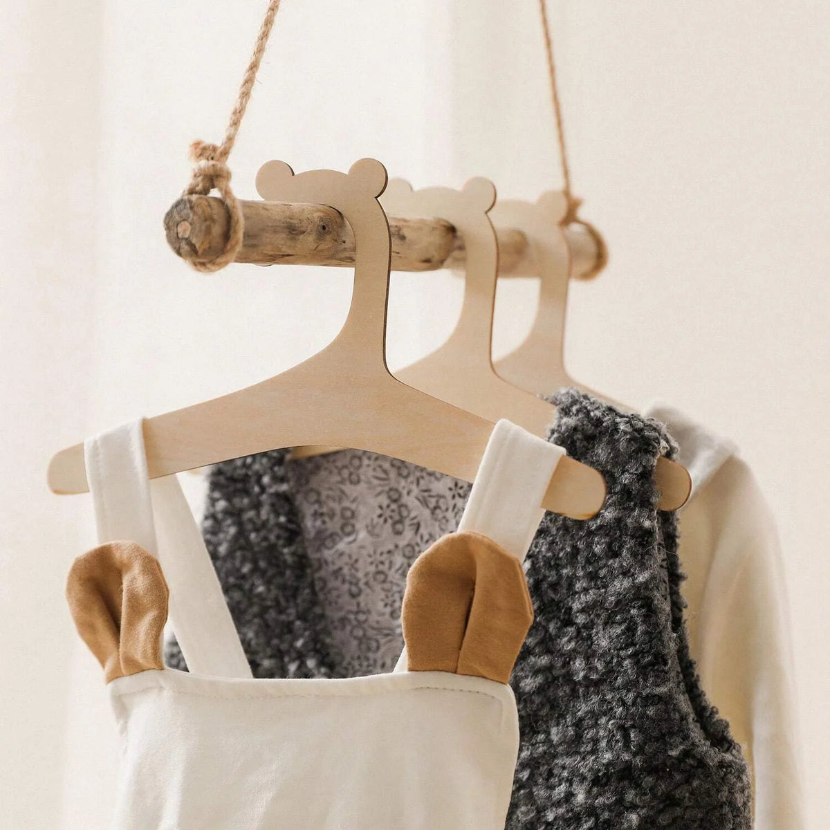 Wooden clothing hangers for kids and apparel hanging from a rope