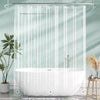 A crystal clear shower curtain with weighted magnets hanging over a white bathtub in a bathroom.