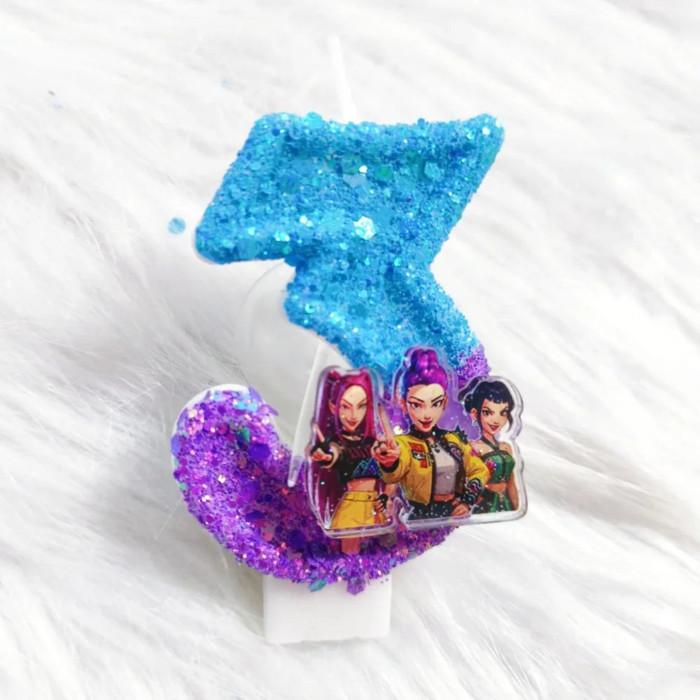 A birthday candle featuring a blue glitter shape and an inset card of three female characters.