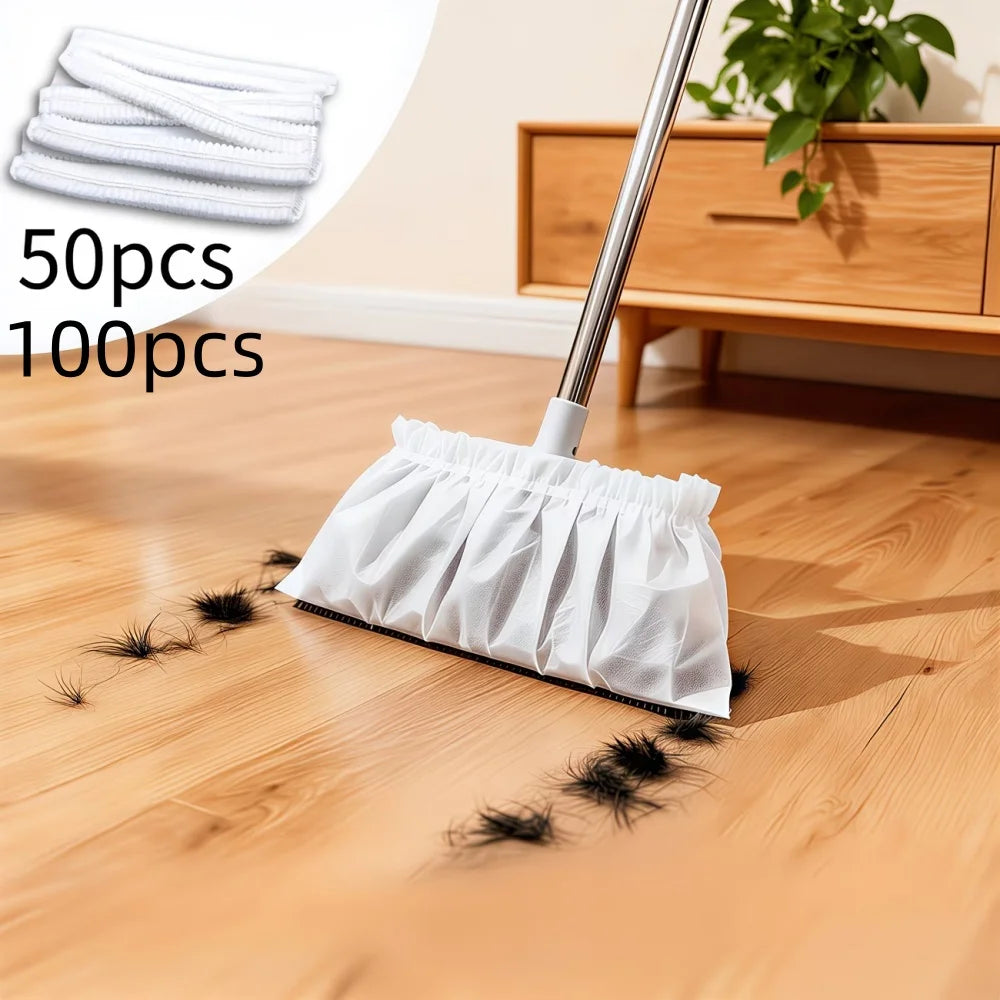 A white disposable electrostatic broom cover is shown on a wooden floor next to a cleaning mop and several stacked white cove