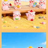 Colección de figuras de cerdo en resina rosa en diversas poses y colores sobre una superficie de madera junto a...