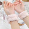 A pair of pink microfiber wrist sweatbands for face washing and skincare are shown on hands.
