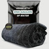 A black microfiber car cleaning towel rolled up, with a bag labeled Absorb up to one gallon of water.