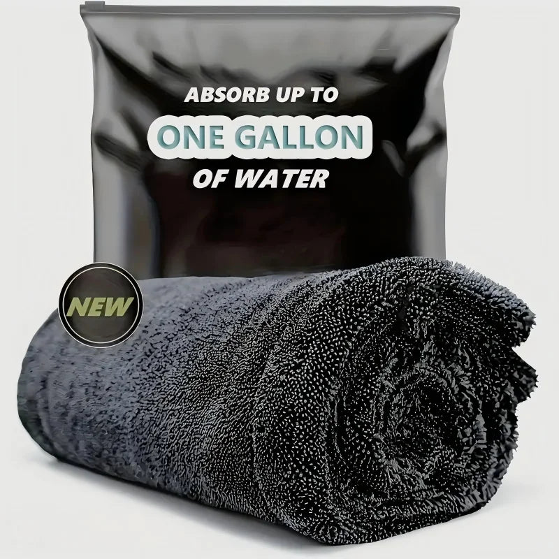 A black microfiber car cleaning towel rolled up, with a bag labeled Absorb up to one gallon of water.
