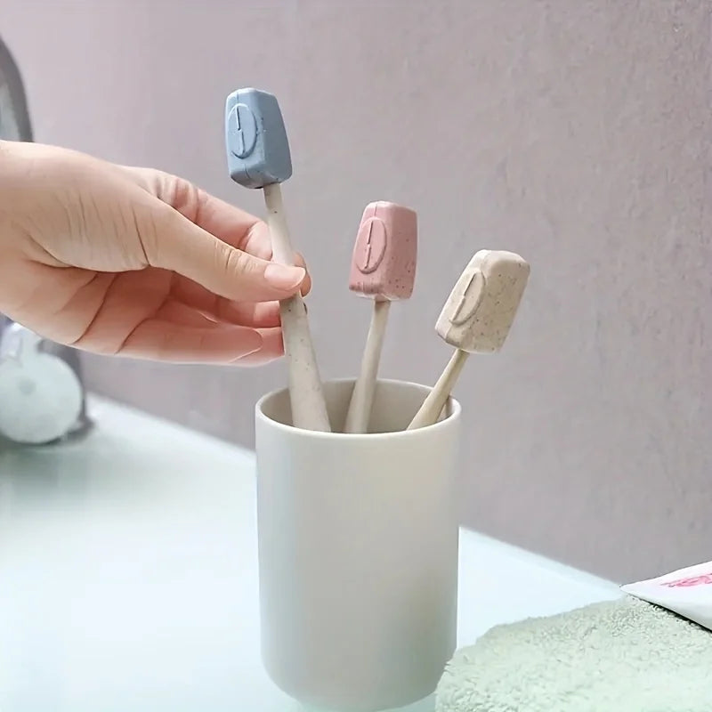 A hand holds four toothbrush head covers in various pastel colors, including blue and pink, above a white cup.