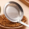 A stainless steel fat skimmer strainer is shown above a pile of round, light brown food items on a wooden board.