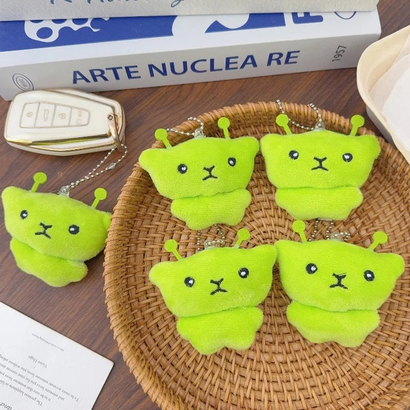 Two bright lime green plush cat keychains are displayed on a woven tray.