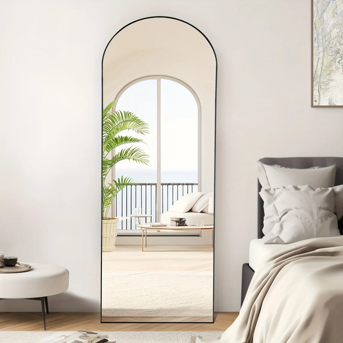 A full length arch mirror with an aluminum frame reflecting a bright interior and outdoor view.