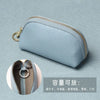A light blue leather key organizer wallet with a zipper closure shown against a muted background.